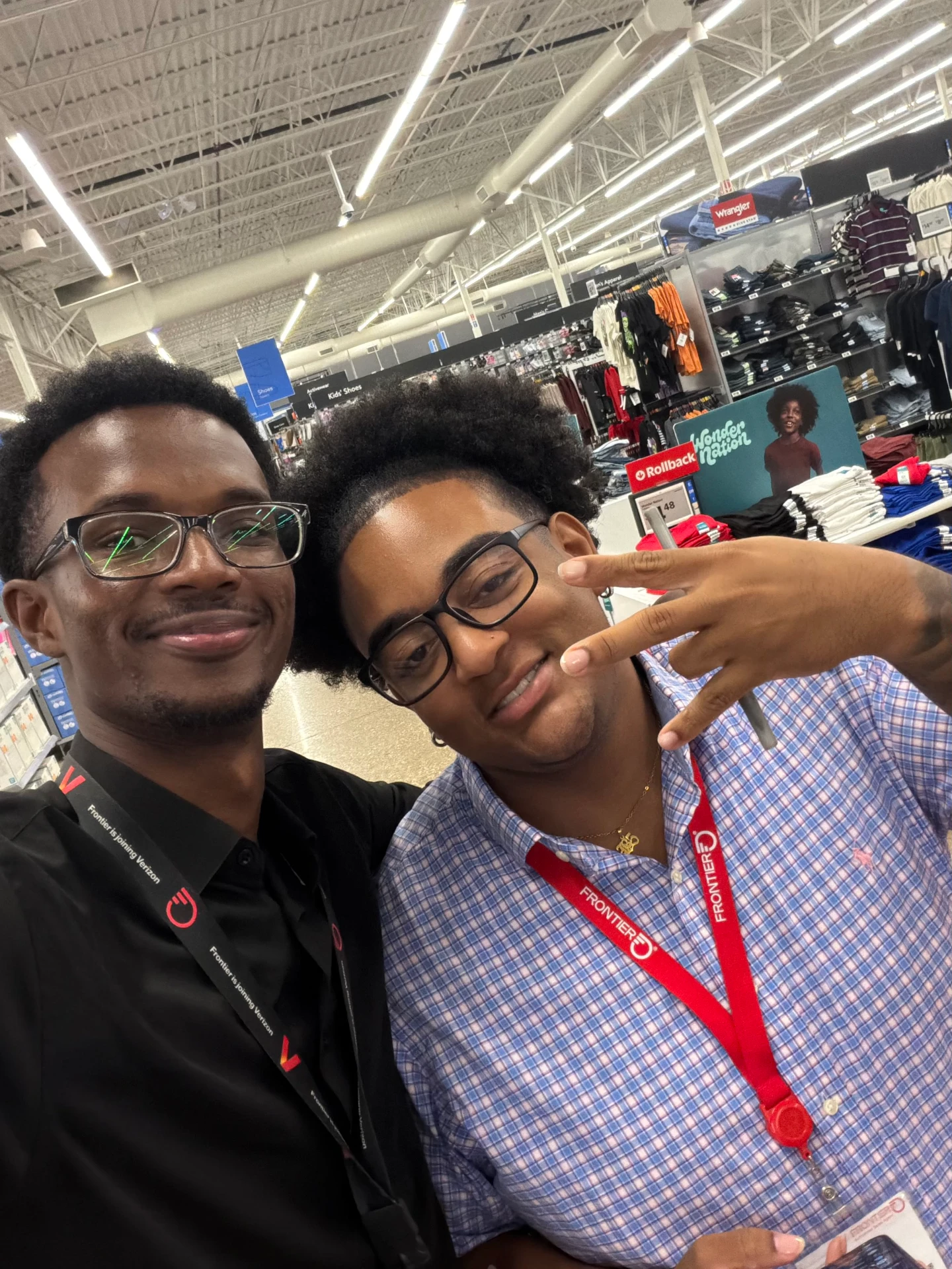Two smiling individuals pose together in a retail store, showcasing a friendly atmosphere and teamwork.